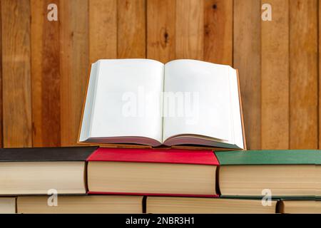 open book with blank pages on top of a stack of books placed in the form of a wall. Stock Photo