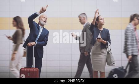 Two traveling business people calling a taxi at the same time at the subway station Stock Photo