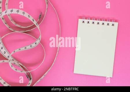 Blank open notebook with centimeter tape on pink background with space for text or business food concept. Concept sport, diet, fitness, healthy eating Stock Photo