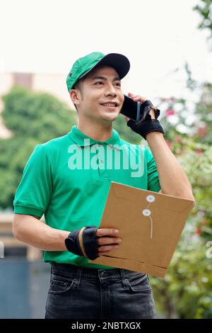 Portrait of delivery man with packed documents talking on phone with client Stock Photo