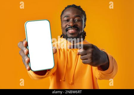 Smiling african man pointing at cellphone with blank screen with copy space Stock Photo