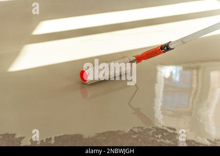 Needle roller for self-leveling floors. Leveling the floors with a cement mixture. Stock Photo