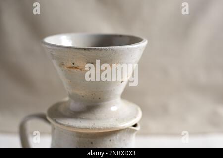 Handmade coffee dripper ceramic on  textile background. Stock Photo