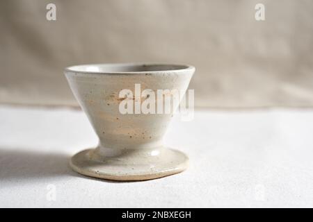 Handmade coffee dripper ceramic on  textile background. Stock Photo