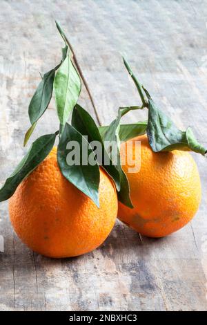Two oranges and their leaves on a background of old boards Stock Photo