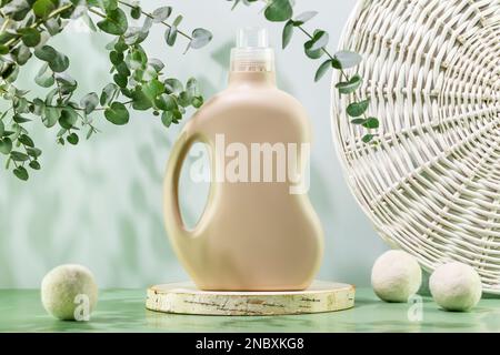 Natural laundry detergent mockup. Washing detergent concept with bottle of washing gel or fabric softener on wooden podium with laundry balls and euca Stock Photo