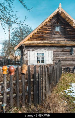 Beautiful old traditional wooden house with clay pots on the fence in the village of Margionys, Dzūkija or Dainava region, Lithuania, in spring Stock Photo