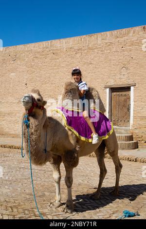 Young Person on Camel, Ichon Qala, UNESCO World Heritage Site, Khiva, Uzbekistan Stock Photo