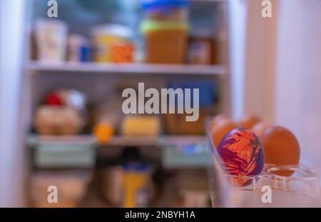 Refrigerator shelf with regular eggs and one painted Stock Photo