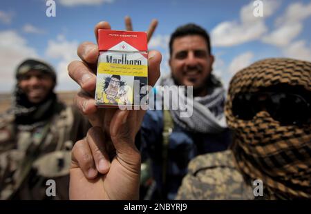 A Libyan Reblel Lights A Cigarette While Watching News Footage On
