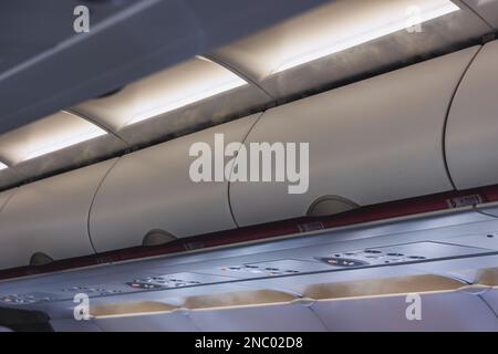 Closed hand luggage compartments in a cabin of passenger plane Stock Photo