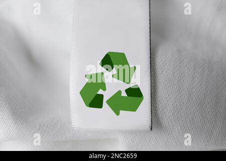 Clothing label with recycling symbol on white shirt, closeup view Stock Photo