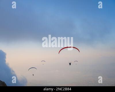 Paragliding in sky. Paraglider tandem flying over sea and mountains in cloudy day. view of paraglider and Blue Lagoon in Oludeniz, Turkey. Extreme spo Stock Photo
