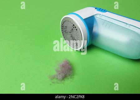 Modern fabric shaver and lint on green background Stock Photo