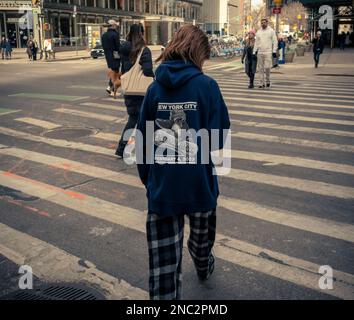 A young woman in Midtown Manhattan in New York on Sunday, February 5, 2023 crosses West 57th Street wearing a commemorative sweatshirt for the previous daysÕ ÒWillÕs Bar MitzvahÓ. (© Richard B. Levine) Stock Photo