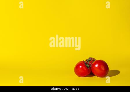 tomatoes vegetables ,three objects,hard shadow,red color round,lie on the surface of the yellow background.concept juice vitamins. Stock Photo