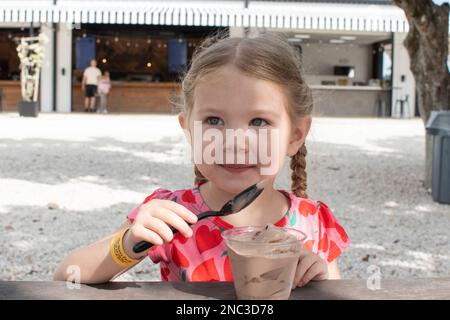 Portrait of a caucasian girl eating ice cream outdoors. Happy child enjoying summer Stock Photo