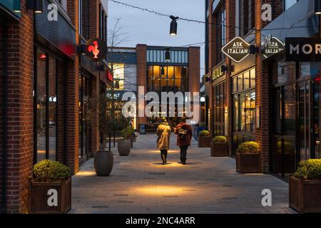 People lit up by spotlights and walking through Bell Court shopping centre at dusk in Stratford upon Avon, England Stock Photo