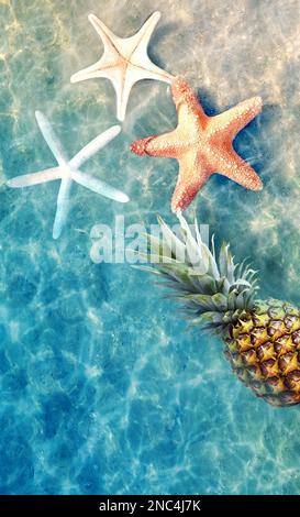 Yellow pineapple and starfish on a blue water background. Exotic concept. Stock Photo