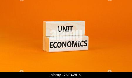 Unit economics symbol. Concept words Unit economics on wooden blocks. Beautiful orange table orange background. Business and unit economics concept. C Stock Photo