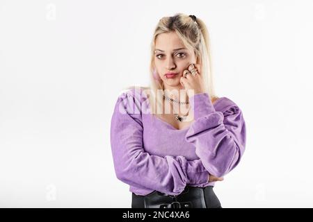 Young caucasian woman wearing blouse standing isolated over white background touches chin with fist and looks very bored. Doesn't believe the lies and Stock Photo
