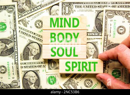 Mind body soul spirit symbol. Concept words Mind Body Soul Spirit on wooden blocks. Beautiful background from dollar bills. Businessman hand. Lifestyl Stock Photo