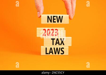 New 2023 tax laws symbol. Concept words New 2023 tax laws on wooden blocks. Beautiful orange table orange background. Businessman hand. Business new 2 Stock Photo