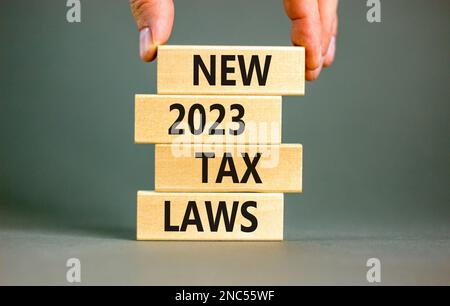 New 2023 tax laws symbol. Concept words New 2023 tax laws on wooden blocks. Beautiful grey table grey background. Businessman hand. Business new 2023 Stock Photo