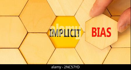 Implicit bias symbol. Concept words Implicit bias on wooden puzzles. Beautiful yellow table yellow background. Businessman hand. Business psychology i Stock Photo