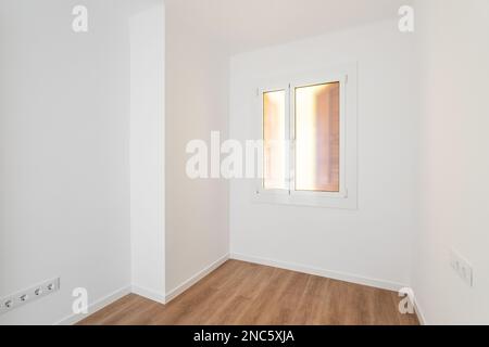 Part of an empty room with white walls, brown parquet. Plastic window in wall with frosted translucent glass. Socket is built into wall for Stock Photo