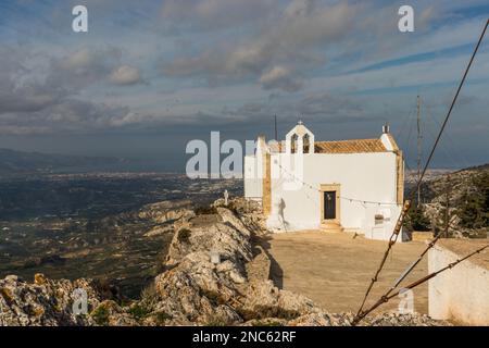 The little church of Afentis Christos on the top of Mount Giuchtas. In the background the city of Heraklion in Crete on a sunny day in December 2019 Stock Photo