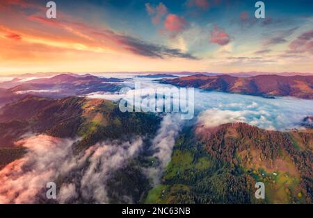 Unbelievable colors sunrise on Carpathian mountains. Fog spreads on the valley of Snidavka village, Ukraine. Spectacular landscape of mountain hills g Stock Photo