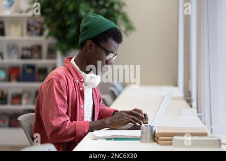 Successful African American guy programmer is typing code in laptop sits in office of IT company Stock Photo