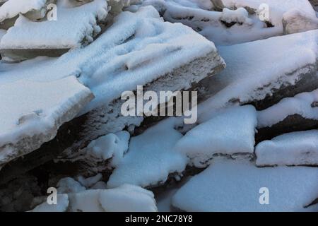 Huge broken ice blocks lie on the river bank under the snow. Spring. Photo in high quality. Horizontal. Texture. Background. Stock Photo