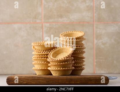 Stack of empty baked round canape baskets on a wooden board, round empty tartlets Stock Photo