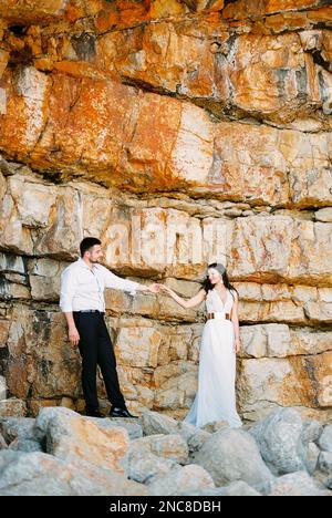 The bride and groom stand holding hands near the railing under the ...