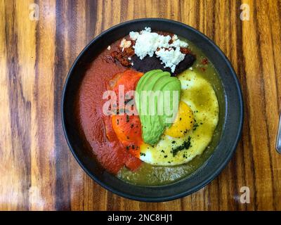 Huevos Divorceados or Divorced Eggs, a traditional Mexican breakfast dish in a restaurant in Oaxaca, Mexico.  Two fried eggs are covered in red and gr Stock Photo