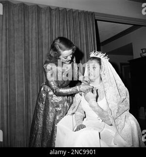 Actress Bette Davis adjusts the wedding gown of her daughter