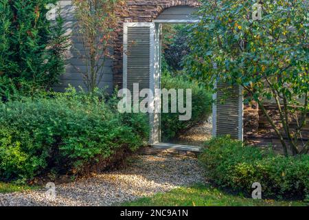 element of landscape design - mirror in the wall od garden - creating the illusion of transition into another space don't existing.  Garden near dacha Stock Photo