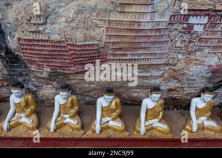 Row of Buddha statues in Kaw Goon cave with carvings in Myanmar. Stock Photo