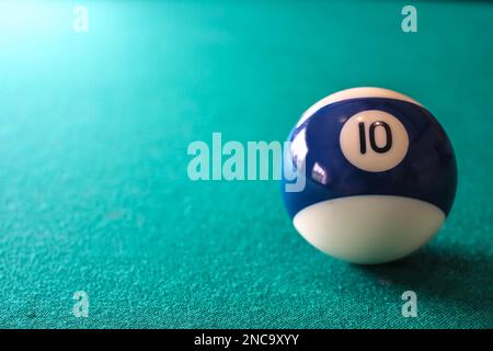 Striped color blue and white billiard ball with number 10 on green table background with copy place for text or design. Stock Photo