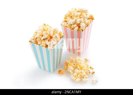 Two pink and blue striped carton buckets with tasty cheese popcorn, isolated on white background. Movies, cinema and entertainment concept. Stock Photo