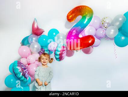 Little girl stand over birthday balloons decorations Stock Photo