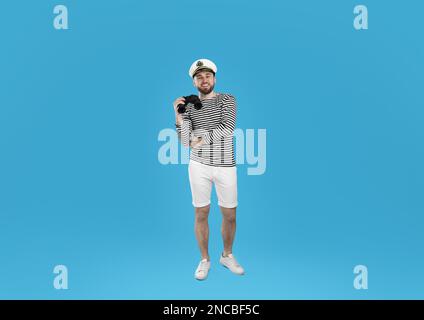 Sailor with binoculars on light blue background Stock Photo