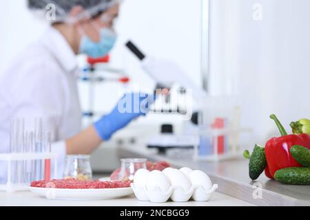 Different food on table and scientist proceeding quality control in laboratory Stock Photo