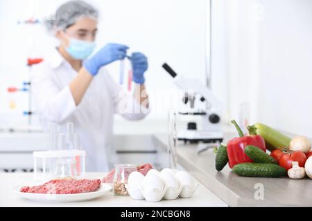 Different food on table and scientist proceeding quality control in laboratory Stock Photo