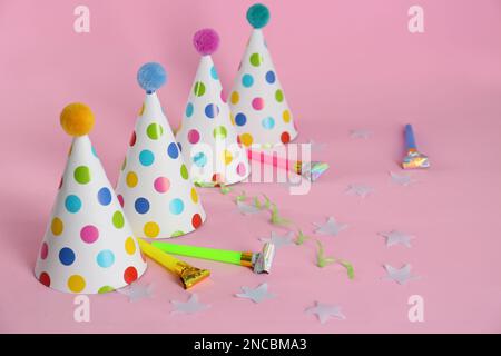 Colorful party hats with fluffy balls and blowers on pink background ...