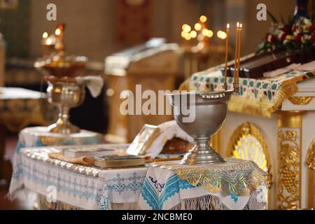 Silver vessel with holy water on stand near altar in church, space for text. Baptism ceremony Stock Photo