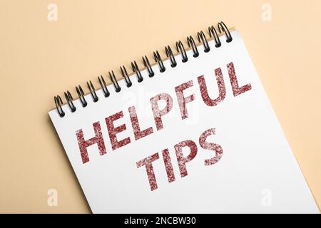 Notebook with phrase Helpful Tips on beige background, top view Stock Photo