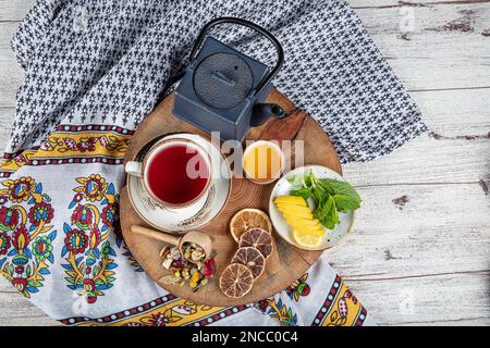 Cast iron blue teapot. Cinnamon sticks, name, Lemon slices and dried ginger on a cutting board. Still life. Cast iron tea pot set with several herbs f Stock Photo